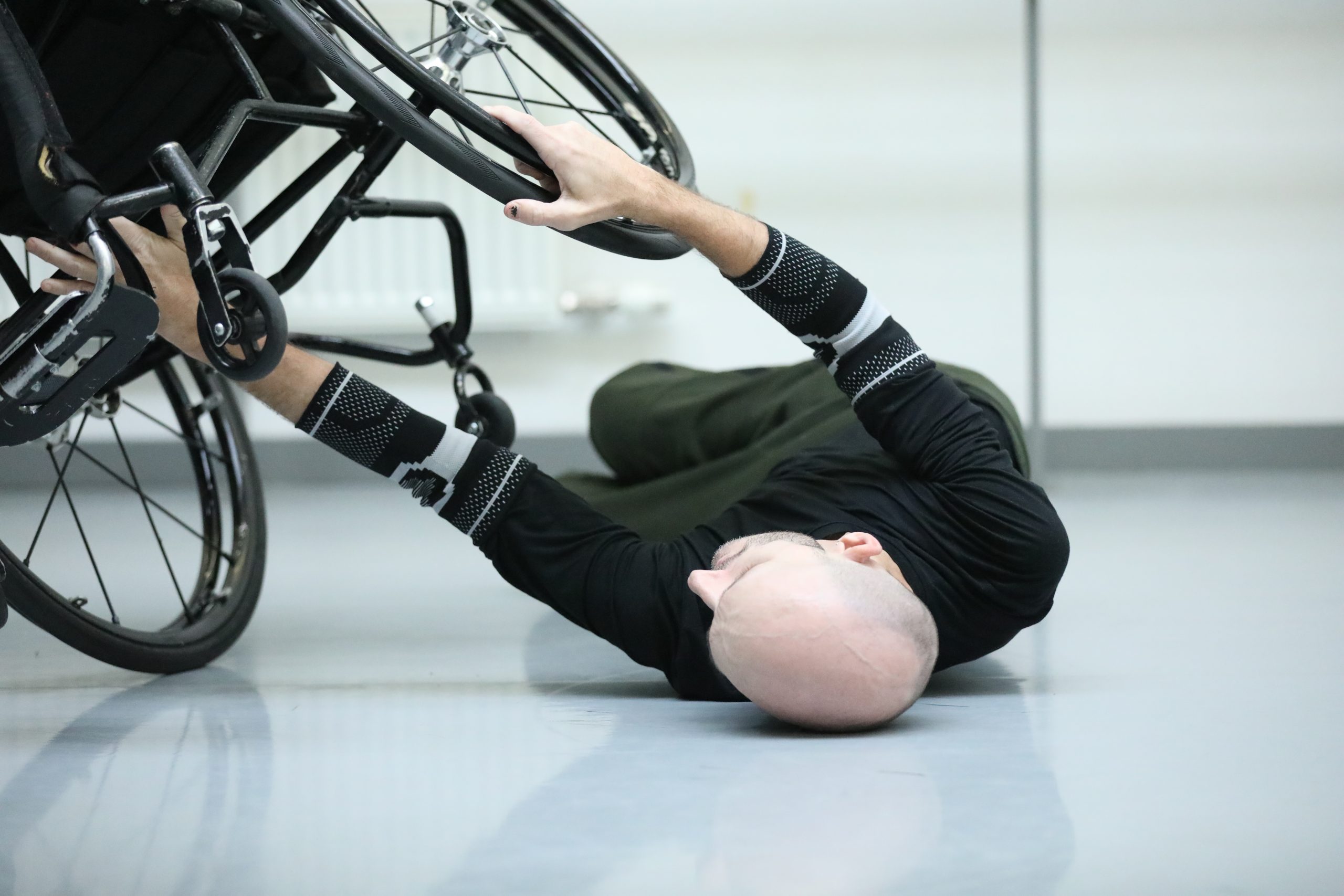In a dance studio Marc counter balances his wheelchair from the floor, where he lies on his back.