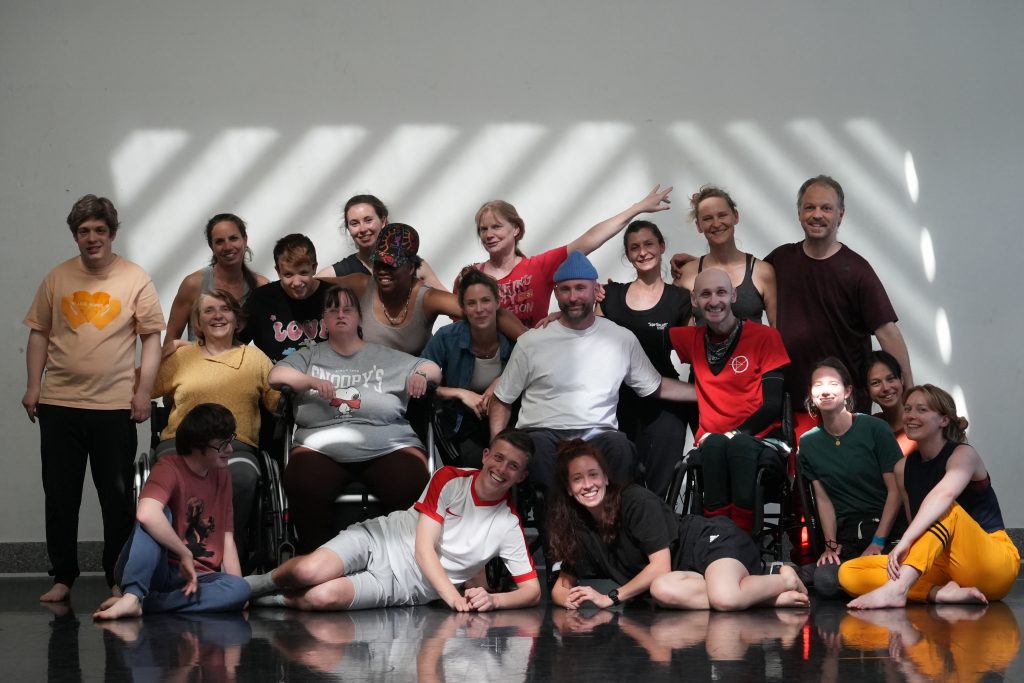 A group photo of Marc and the workshop participants. The group have their arms round each others shoulders and are all smiling.
